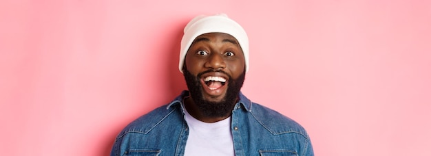 Close-up van opgewonden bebaarde afro-amerikaanse man in beanie die naar de camera staart, drukt verbazing en vreugde uit