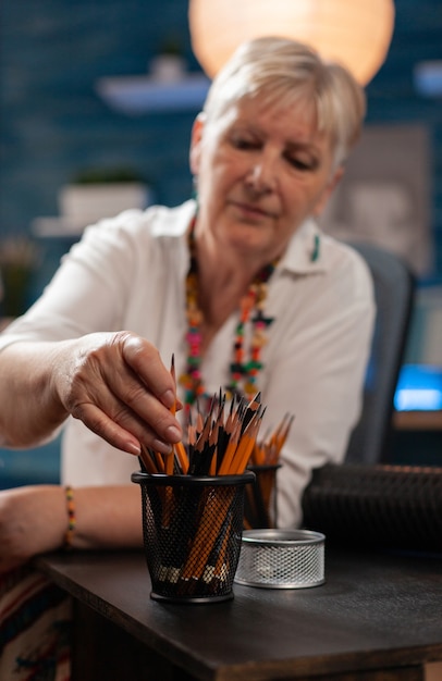 Close up van oudere kunstenaar met potloden op tafel in studio