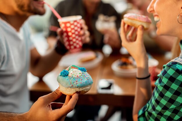 Close-up van paar dat geglazuurde donuts eet