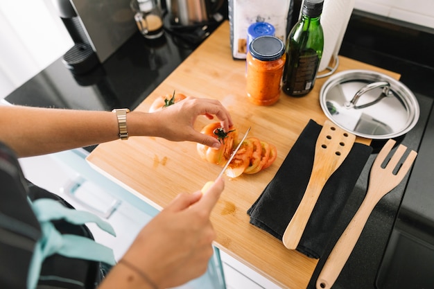 Close-up van plakken van de vrouwen scherpe tomaat op keukenteller