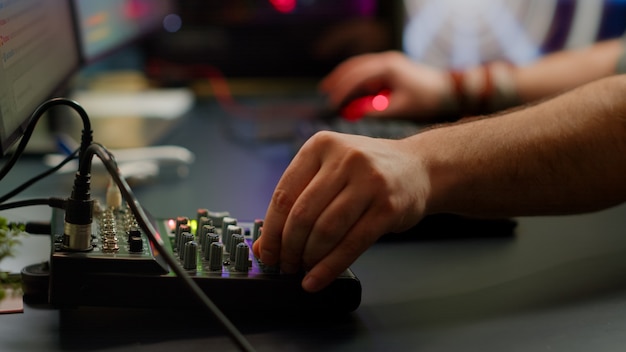 Close-up van professioneel toetsenbord met RGB-verlichtingsstreaming tijdens chat. Speler die krachtige spelcomputer gebruikt in thuisstudio van esport-videogame die typt op toetsenbord met space shooter-videogame.