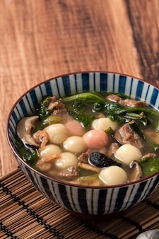Close up van rode en witte tangyuan (tang yuan, kleverige rijst knoedel ballen) met hartige soep in een kom op houten tafel achtergrond voor winterzonnewende festival voedsel.