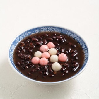Close up van rode en witte tangyuan (tang yuan, kleverige rijst knoedel ballen) met zoete rode bonensoep in een kom op witte tafel achtergrond voor winterzonnewende festival voedsel.