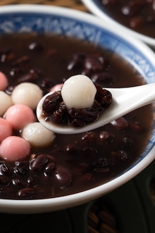 Close up van rode en witte tangyuan (tang yuan, kleverige rijst knoedel ballen) met zoete rode bonensoep in een kom op witte tafel achtergrond voor winterzonnewende festival voedsel.