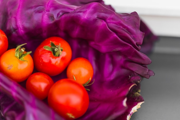 Gratis foto close-up van rode tomaten op purpere koolbladeren