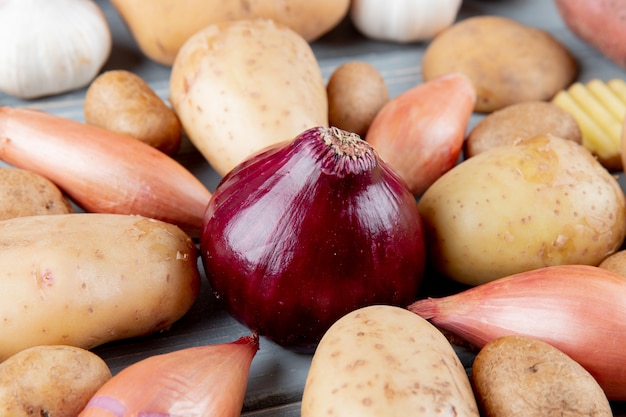 Close-up van rode ui met sjalotten en aardappelen rond op houten achtergrond