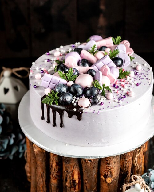 Close up van romige cake in lila versierd met lila roze decoraties en druivenmost