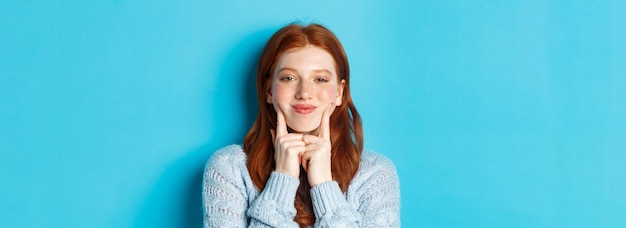 Close-up van schattig en dwaas meisje met rood haar porren wangen met kuiltjes en glimlachen staande weer