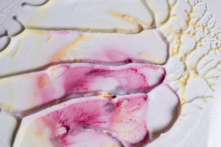 Gratis Foto close-up van schuimoppervlak met roze en gele verfkleuren