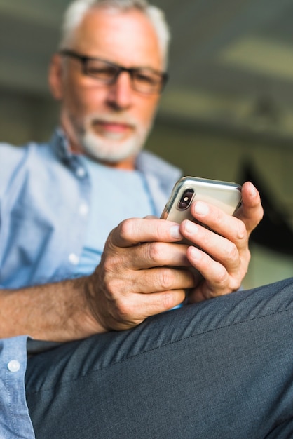 Gratis foto close-up van senior man's hand met mobiele telefoon