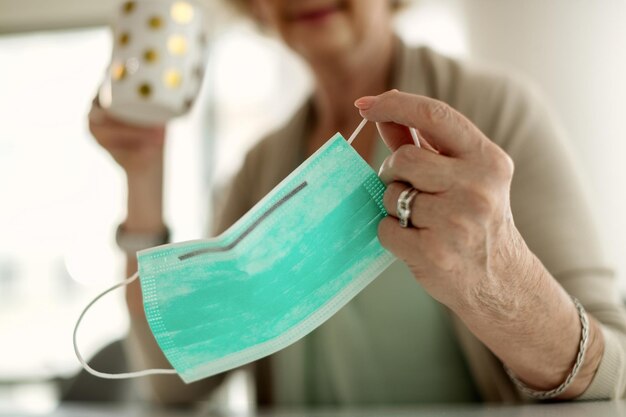 Close-up van senior vrouw met beschermend gezichtsmasker thuis