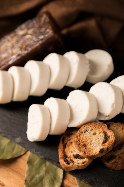 Close-up van smakelijke geitenkaasstukjes en geroosterd brood op zwart dienblad