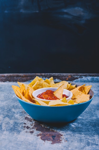 Close-up van smakelijke nachos en kom met salsa saus op metalen tafel