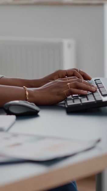 Close-up van tiener met donkere huid handen op toetsenbord e-mail typen op computer werken bij onderwijs een...