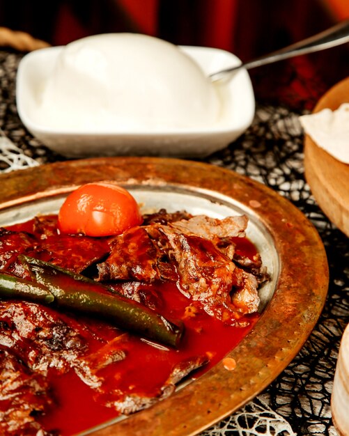 Close up van Turkse iskender kebab gegarneerd met tomatensaus en gegrilde peper