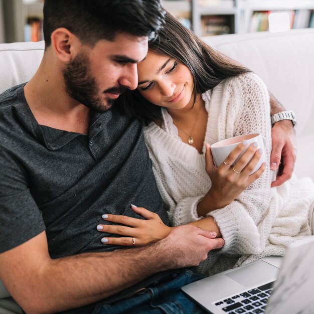 Close-up van verliefde paar zittend op de bank kijken naar laptop