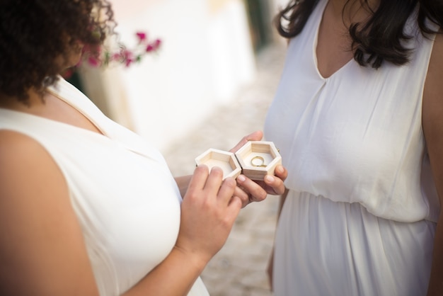 Close-up van verlovingsringen in speciale doos. vrouw in trouwjurk met houten kist