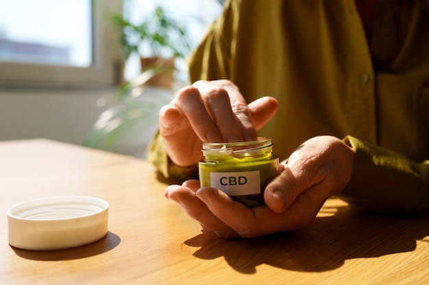 Gratis foto close-up van vrouw die cbd-crème gebruikt tegen pijn