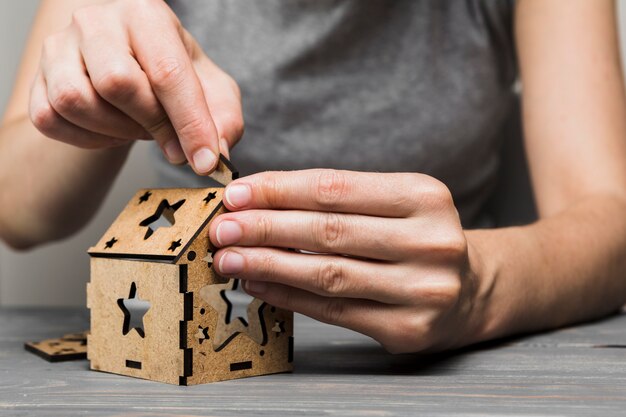 Close-up van vrouw die met de hand gemaakt huis op tafel