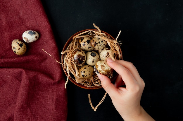 Close-up van vrouw hand met ei met kom eieren met nest op Bourgondië en zwart