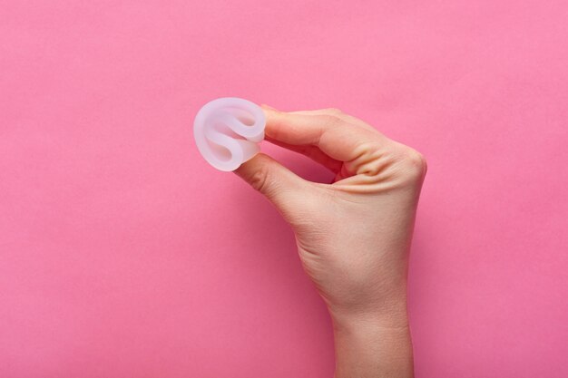 Close-up van vrouw met menstruatiecup geïsoleerd over roos, de periode van de vrouw, menstruatiecup in handen