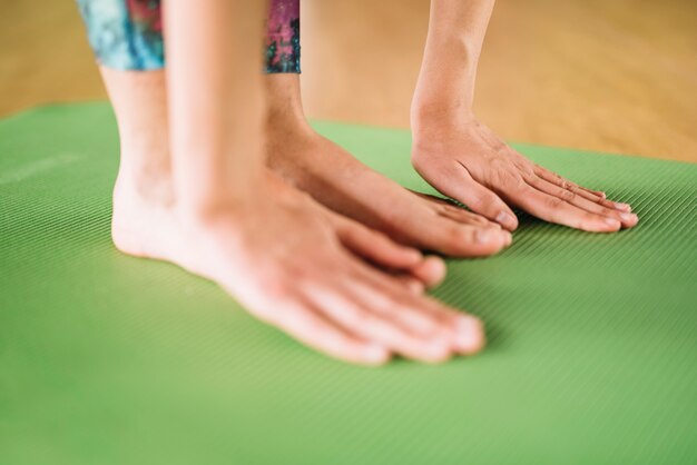 Close-up van vrouw voeten en handen praktijk yoga op groene mat