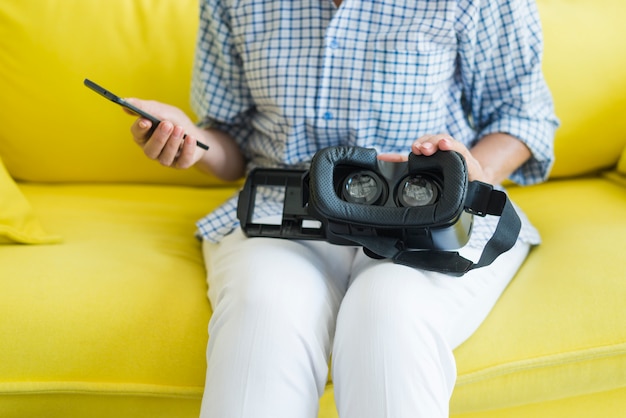 Close-up van vrouw zittend op de Bank met smartphone en virtuele camera