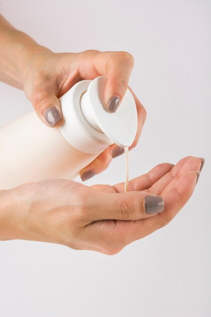 Close-up van vrouwelijke handen met behulp van handdesinfecterend gel pomp dispenser