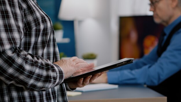 Close-up van vrouwelijke handen met tabletcomputer die grafieken analyseert die op de werkplek van thuis staan terwijl