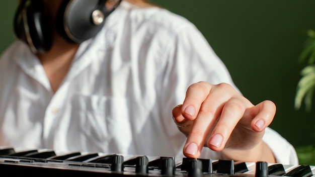 Gratis foto close-up van vrouwelijke muzikant met pianotoetsenbord en koptelefoon binnenshuis