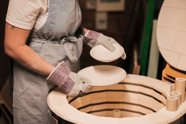 Close-up van vrouwelijke pottenbakker die de ceramische platen schikken