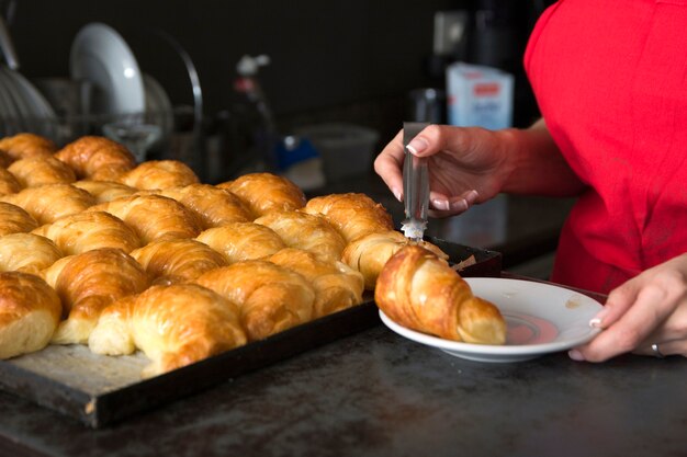 Close-up van vrouwelijke serveerster die croissant in de plaat plaatst