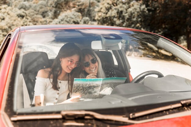 Close-up van vrouwelijke vrienden die in de auto zitten die kaart bekijken