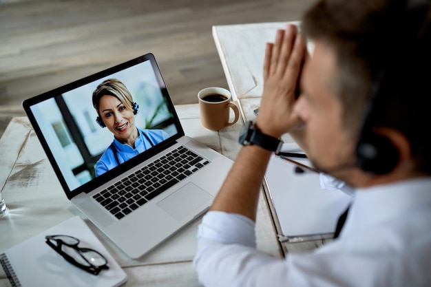 Close-up van zakenman die computer gebruikt terwijl hij een videogesprek voert met zijn arts van kantoor