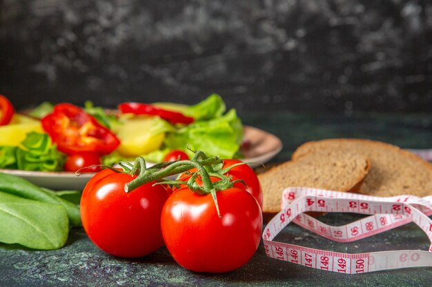 Close-up van zwart brood plakjes verse tomaten met stengel en meter groene bundel op donkere kleuren oppervlak