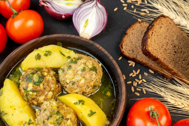 Close-up van zwart brood sneetjes heerlijke gehaktballen maaltijd met aardappelen, groene en verse groenten op zwarte achtergrond