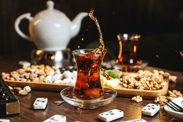 Close-up van zwarte thee in armudu glas met verschillende zoetigheden op tafel