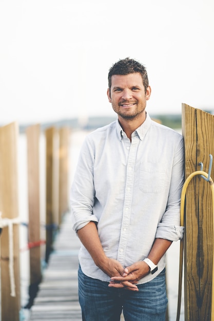 Gratis foto close-up verticaal portret van een knappe volwassen man die zich voordeed op een pier