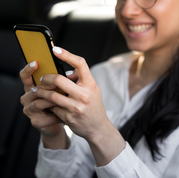 Close-up wazig meisje met behulp van haar mobiele telefoon in de auto