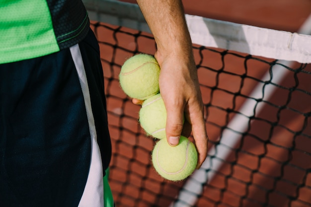 Close-up weergave van tennisspeler met drie ballen