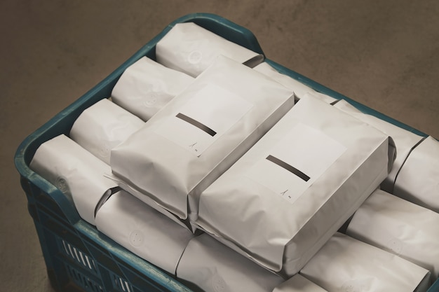 Close-up wit gevuld met koffie of thee verzegelde pakketten in plastic doos op betonnen vloer in magazijn.