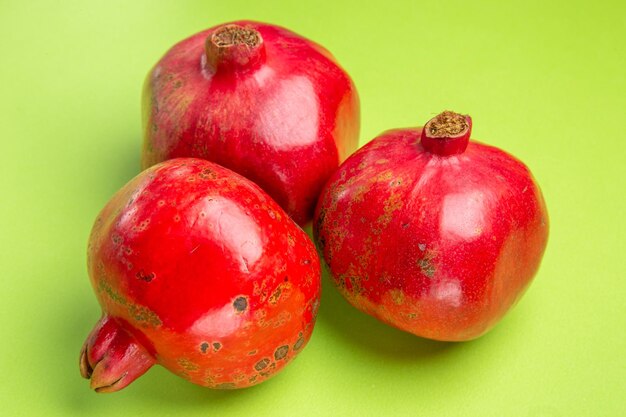 Close-up zijaanzicht granaatappels drie granaatappels op het groene oppervlak
