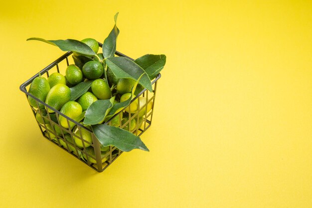 Close-up zijaanzicht groene vruchten grijze mand van de smakelijke groene vruchten met bladeren