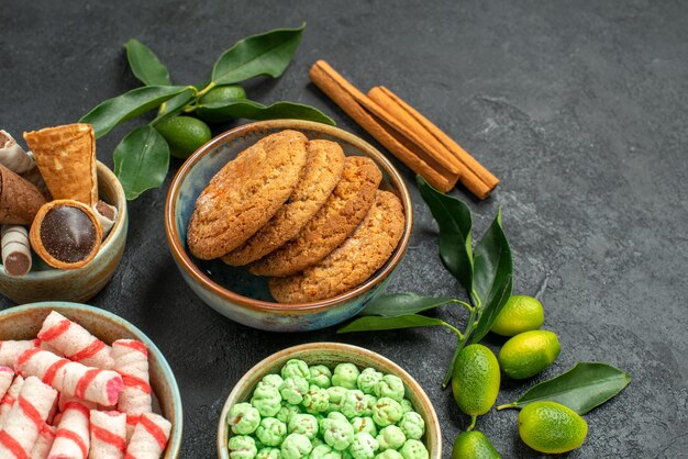 Close-up zijaanzicht snoepjes kaneelstokjes kleurrijke snoepjes citrusvruchten wafels koekjes