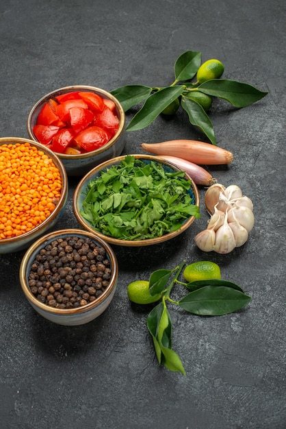 Close-up zijaanzicht specerijen linzen specerijen kruiden uien tomaten knoflook citrusvruchten met bladeren