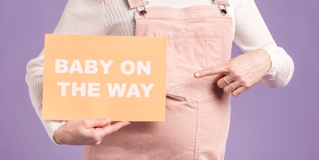 Close-up zwangere vrouw die op papier met baby op het manierbericht richten