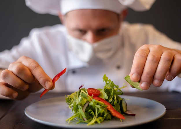 Close-upchef-kok die met masker schotel voorbereidt