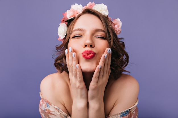 Close-upfoto van aantrekkelijke europese dame met rozen in kort haar. gelukkig wit meisje in krans poseren.