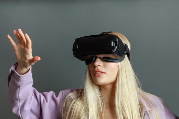 Close-upfoto van een jonge dame die een VR-bril draagt en haar hand openhoudt