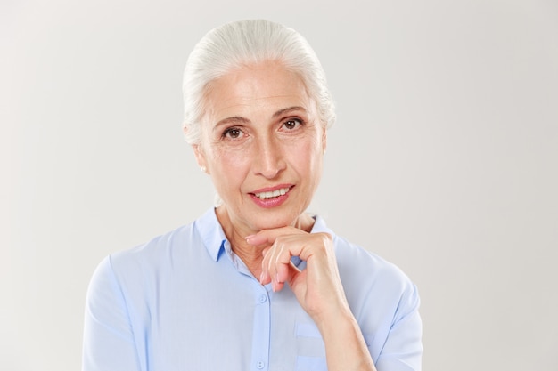 Close-upfoto van elegante cherrful oude dame, die haar kin houdt